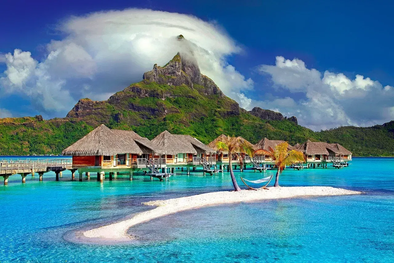Overwaterbungalows en een wit zandstrand aan een turquoise lagune bij Bora Bora