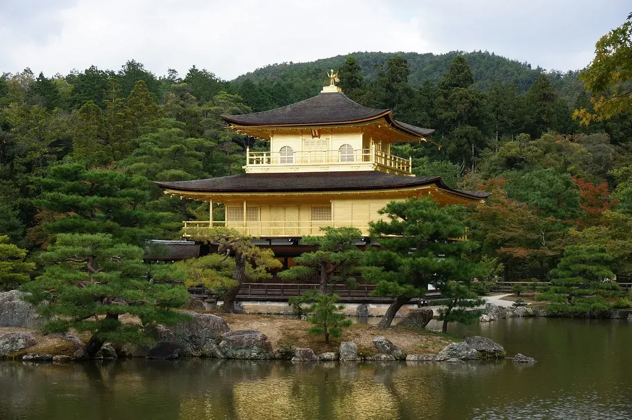 Gouden paviljoen aan een vijver tussen de bomen in Kyoto